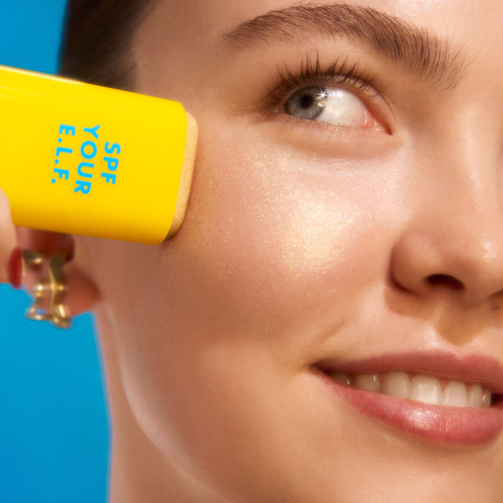 Close-up of a woman applying Invisi-Stick Glitz SPF 50 broad-spectrum sunscreen - light skin tone