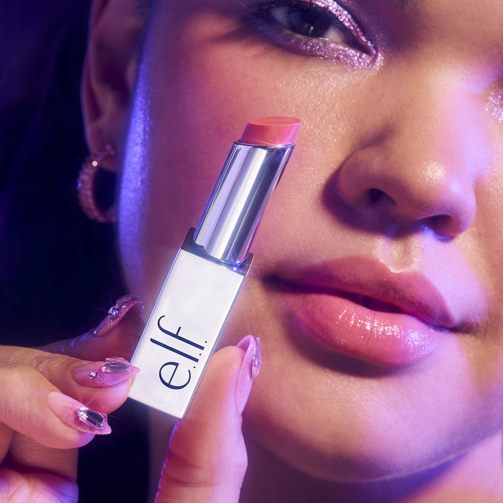 Close up of woman wearing and holding e.l.f. Glow Reviver Lip Oil Stick