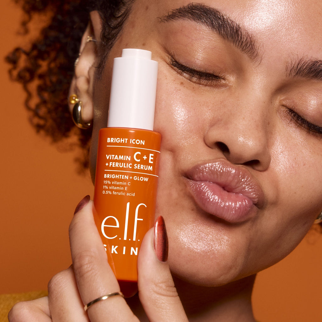 Woman holding an e.l.f. Skin Vitamin C+E serum bottle against her face