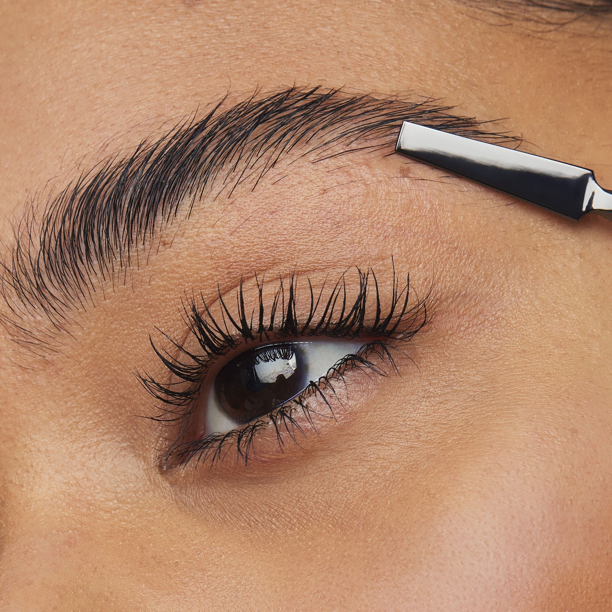 Model applying brow gel with an applicator for laminated eyebrows