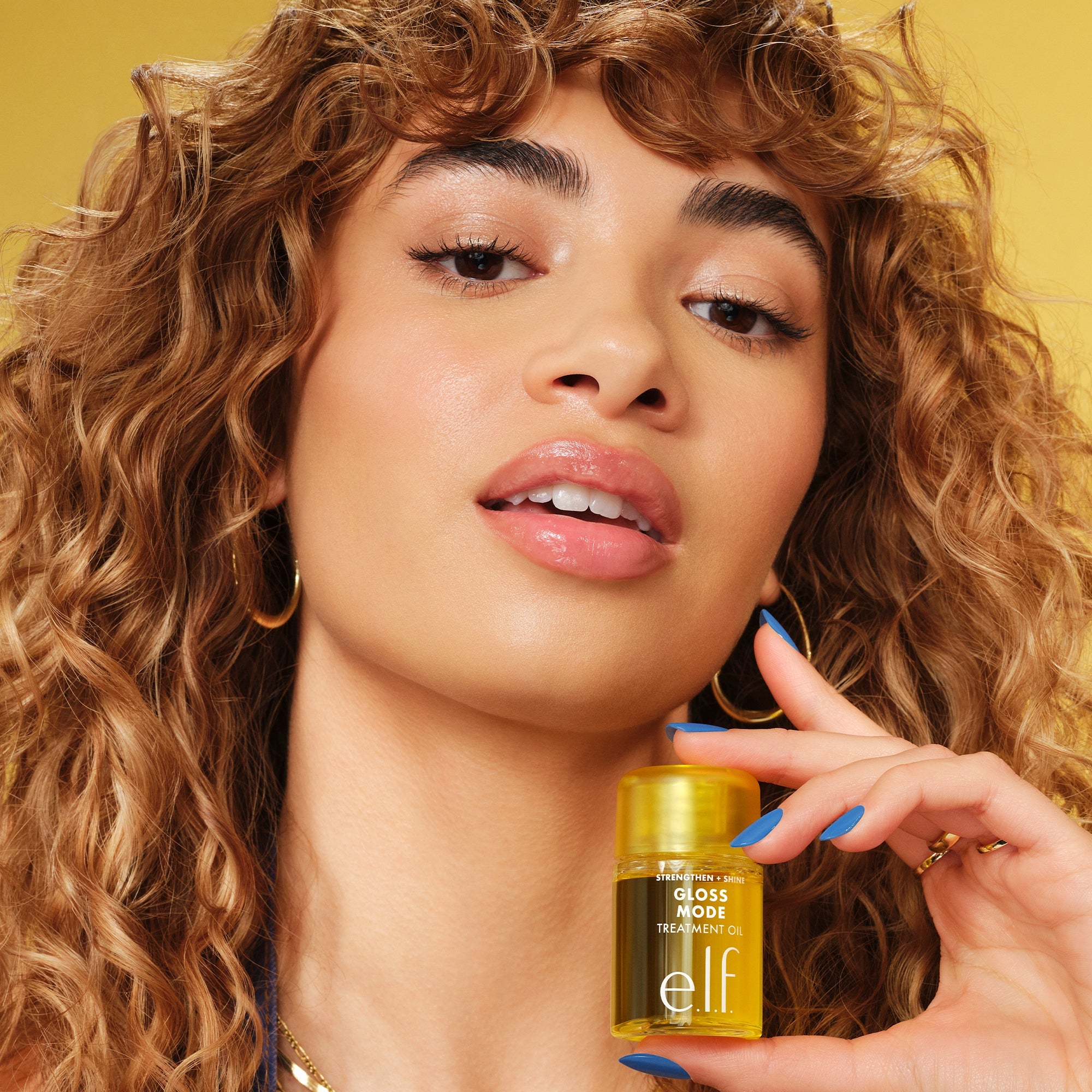 Woman with Curly Hair Holding Gloss Mode Hair Treatment Oil
