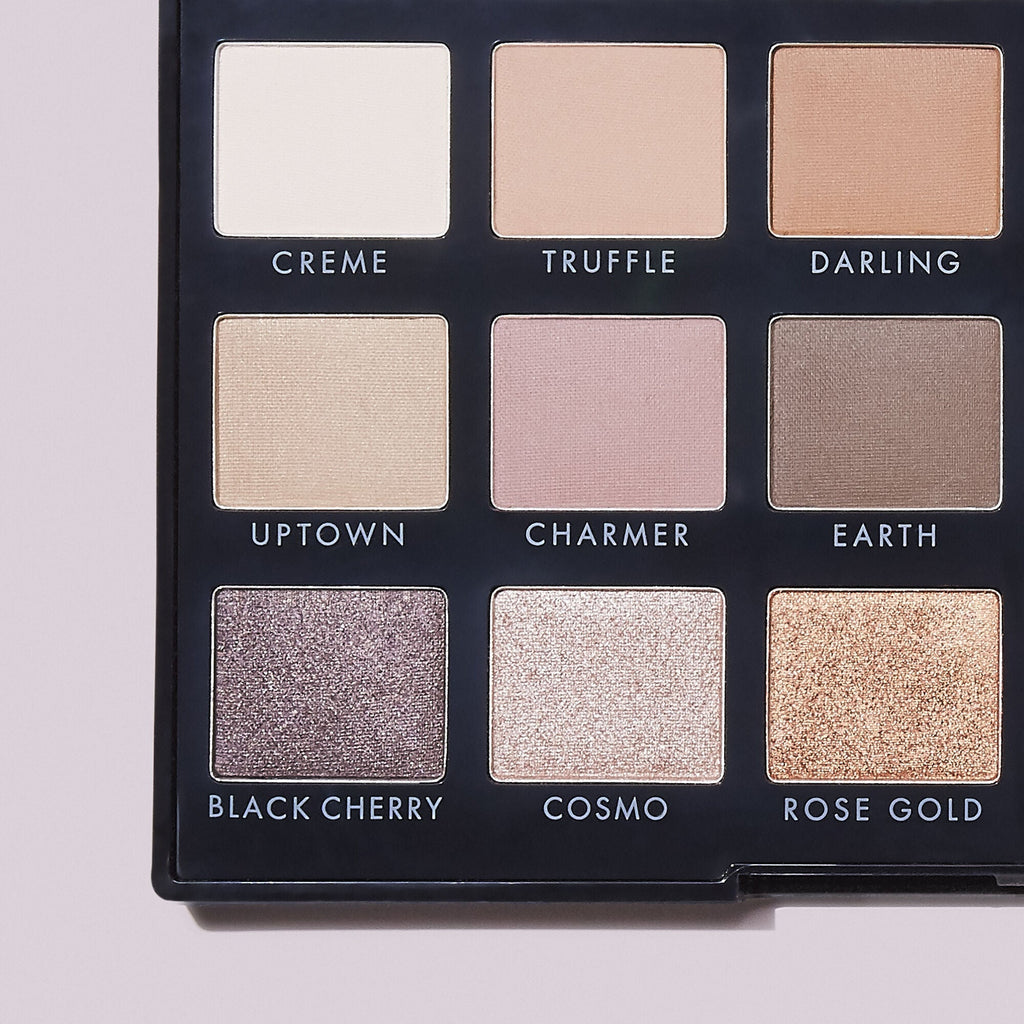Makeup palette with nine eyeshadow color swatches labeled on a light pink background