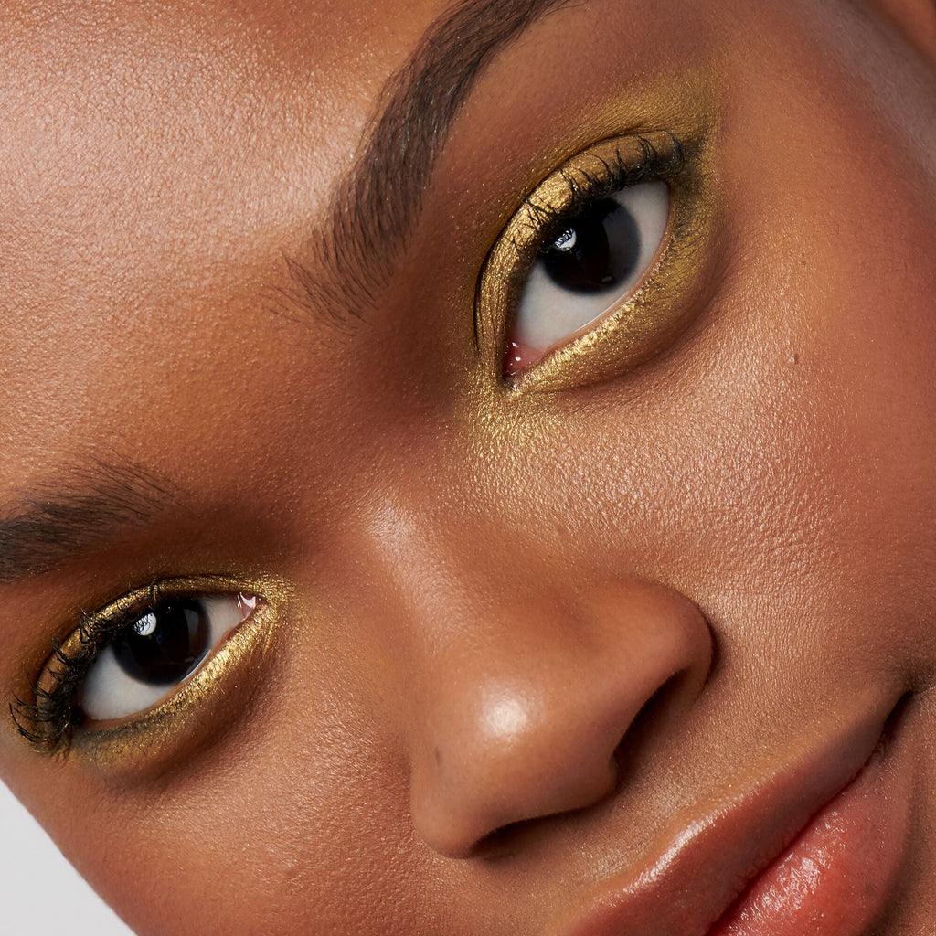 Close-up of a person's face with gold eye makeup